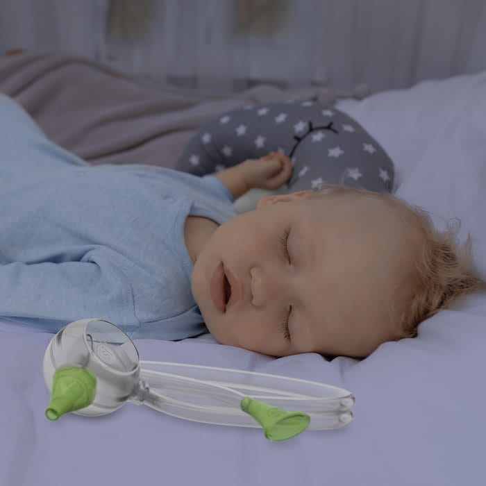 Csecsemő kisfiú békésen alszik, mellette Nosiboo Eco kézi orrszívó