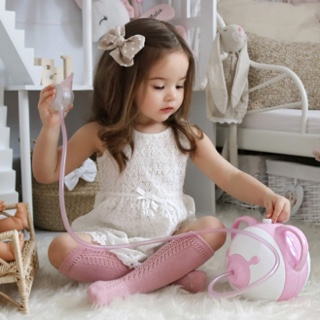 Kislány a babaszobában játszik, kezében Nosiboo Pro pink orrszívó
