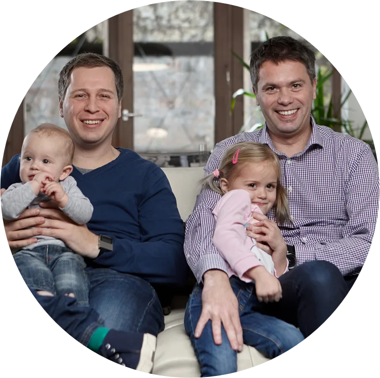Two fathers, inventors of the Nosiboo products, sitting on a couch with their children and smiling