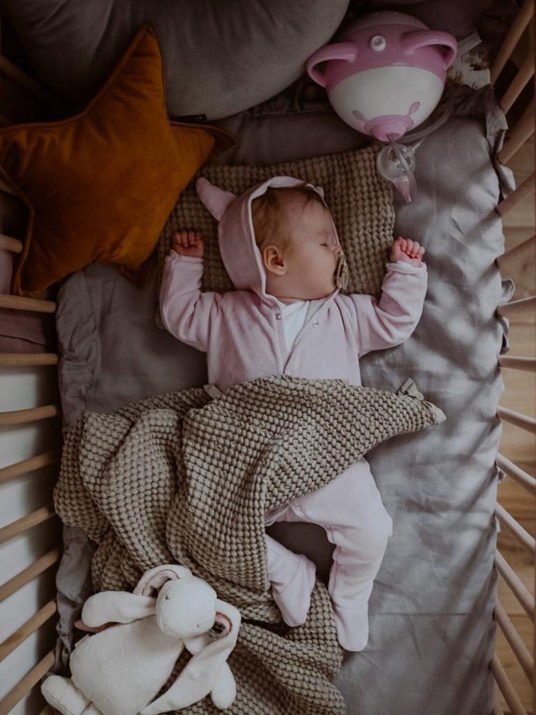 Mózeskosárban csecsemő alszik, mellette Nosiboo Pro elektromos orrszívó