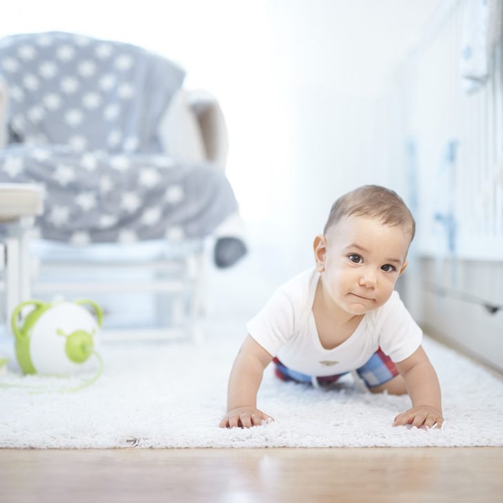 A little boy on a carpet, a green Nosiboo Pro electric nasal aspirator in the background