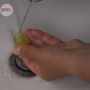 Egy nő kefével tisztítja a Nosiboo Pro2 szipkavégét.